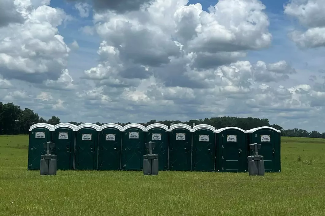 Row of Princess Portable Toilet company toilets in a field