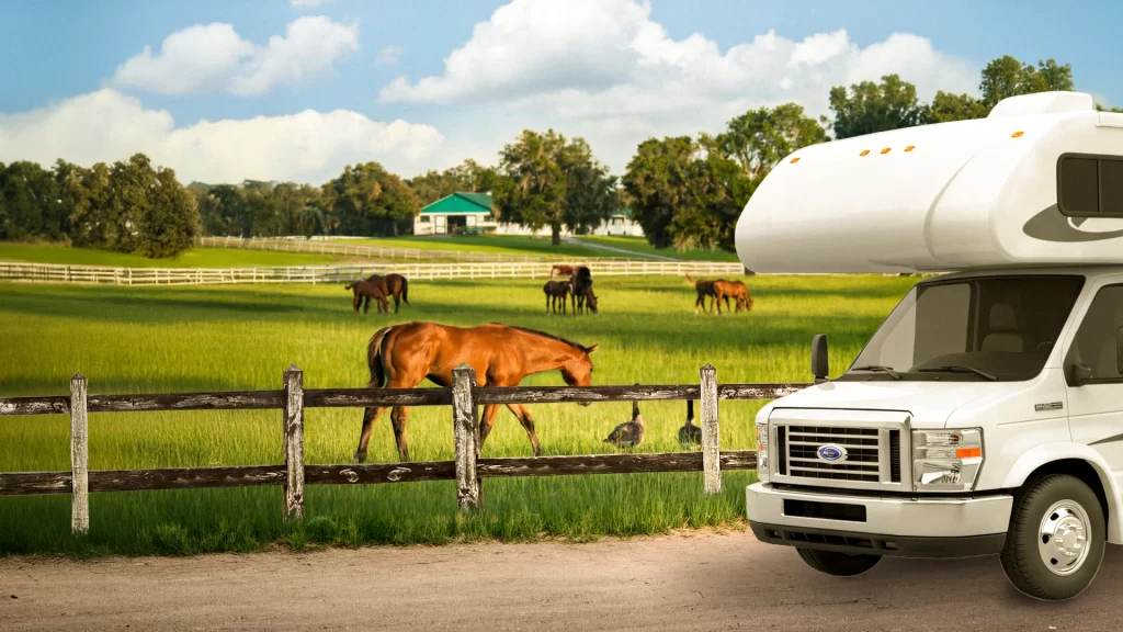 A peaceful farm scene with horses grazing in an open field while an RV is parked nearby, highlighting a rural outdoor setting